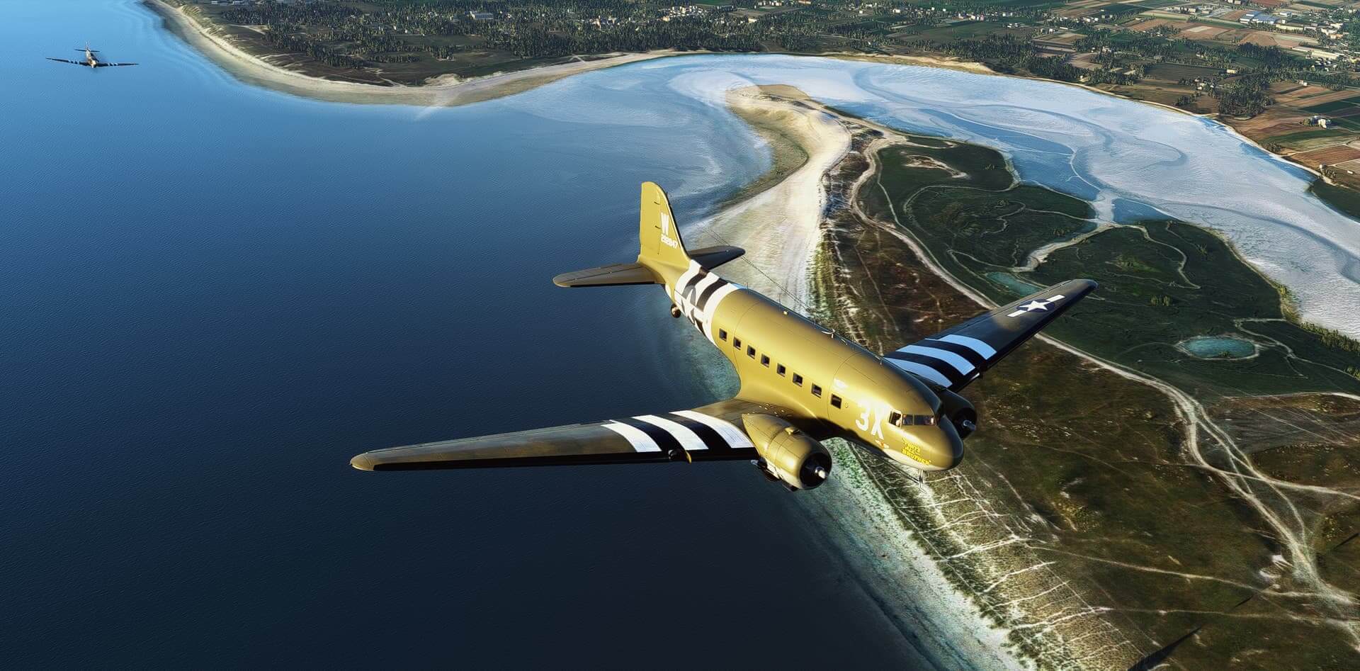 A C-47D Skytrain flies ahead of a Spitfire following behind, following a coast line.