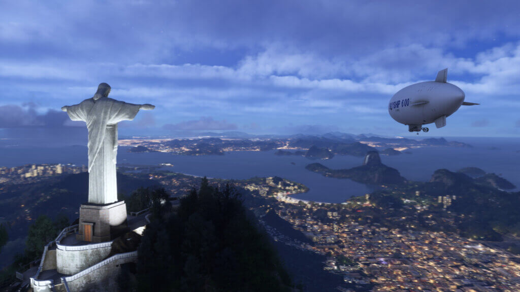 A Skyship 600 flies close to Christ the Redeemer, with the city lights of Rio De Janeiro below