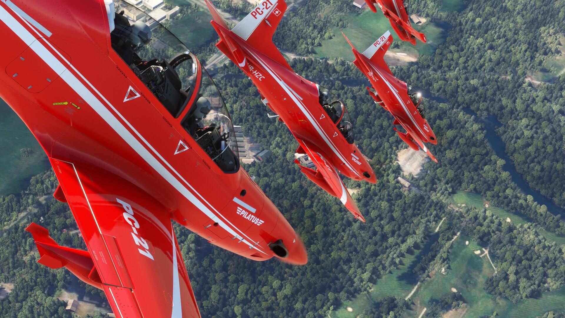 Four PC-21s in red paint fly in close formation facing towards the ground during an airshow