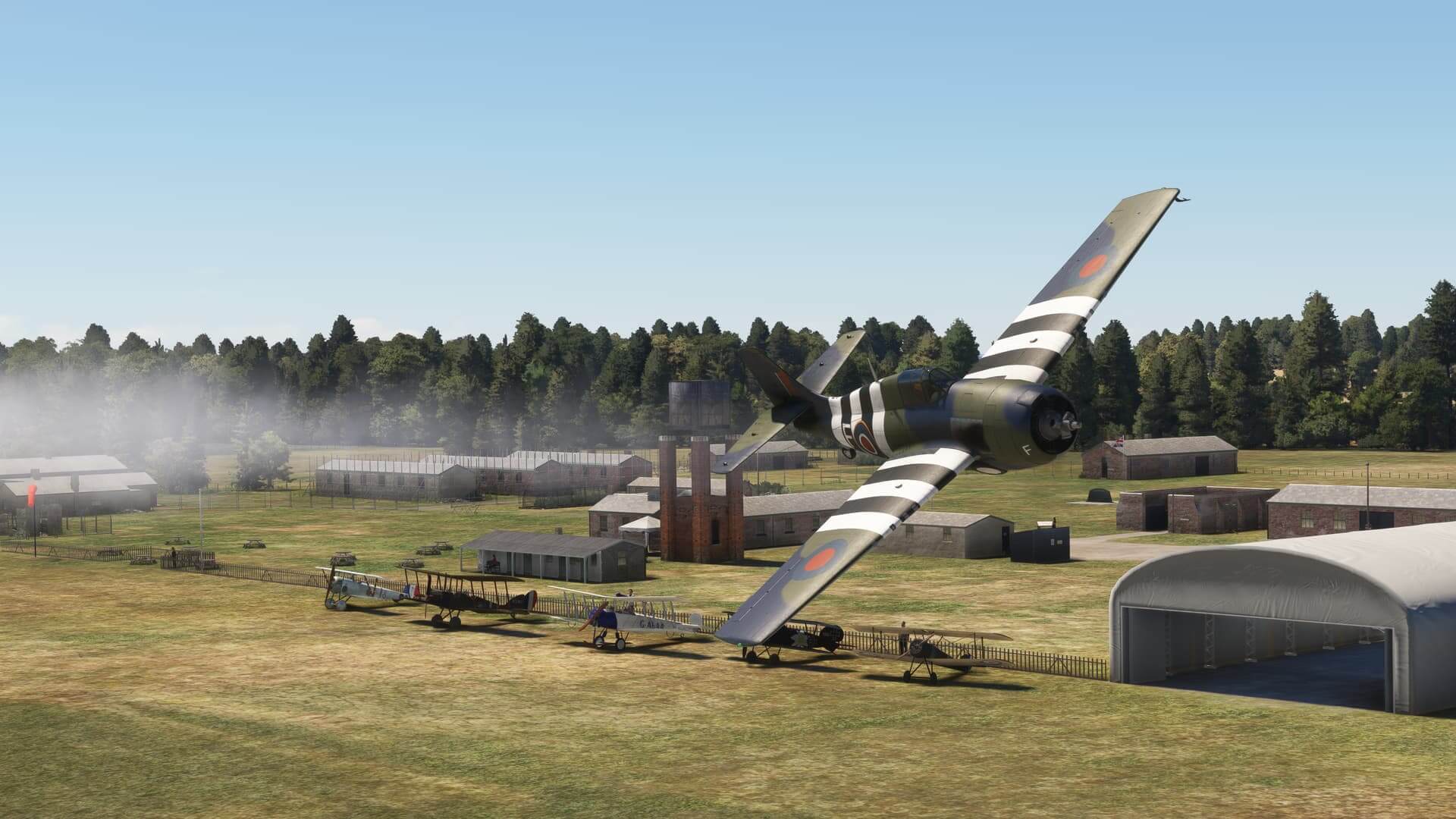 A World War 2 fighter banks right whilst flying over an airfield with more retro warbirds below