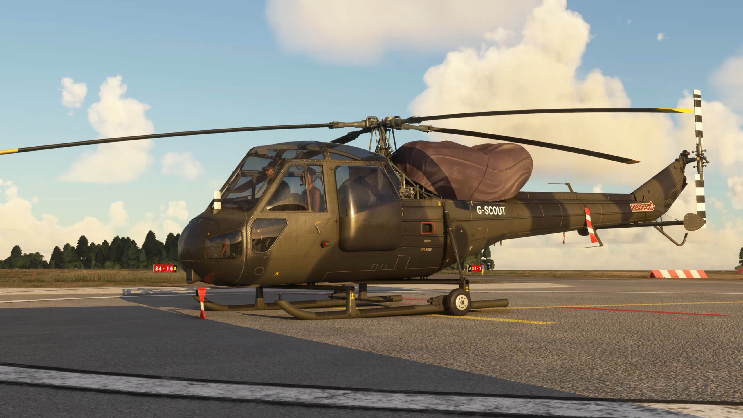 A Westland Scout sits on a helipad with pilots in the cockpit