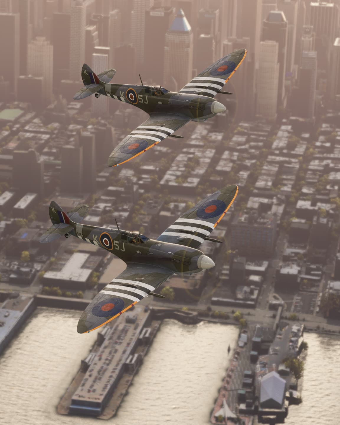 Two Spitfires fly in close formation over the top of a busy cityscape