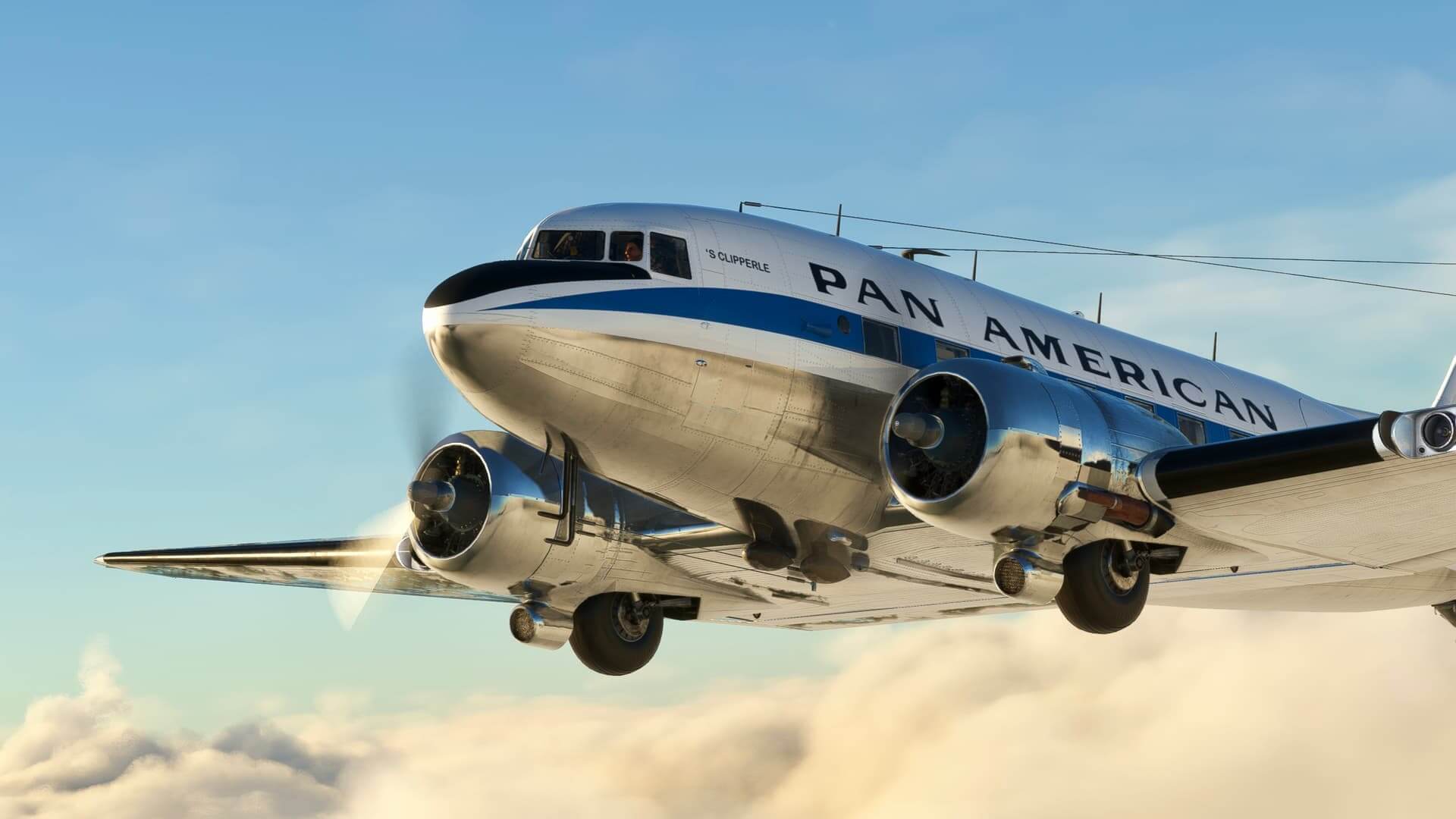 A DC-3 flies over a cloud with a blue sky in the background.