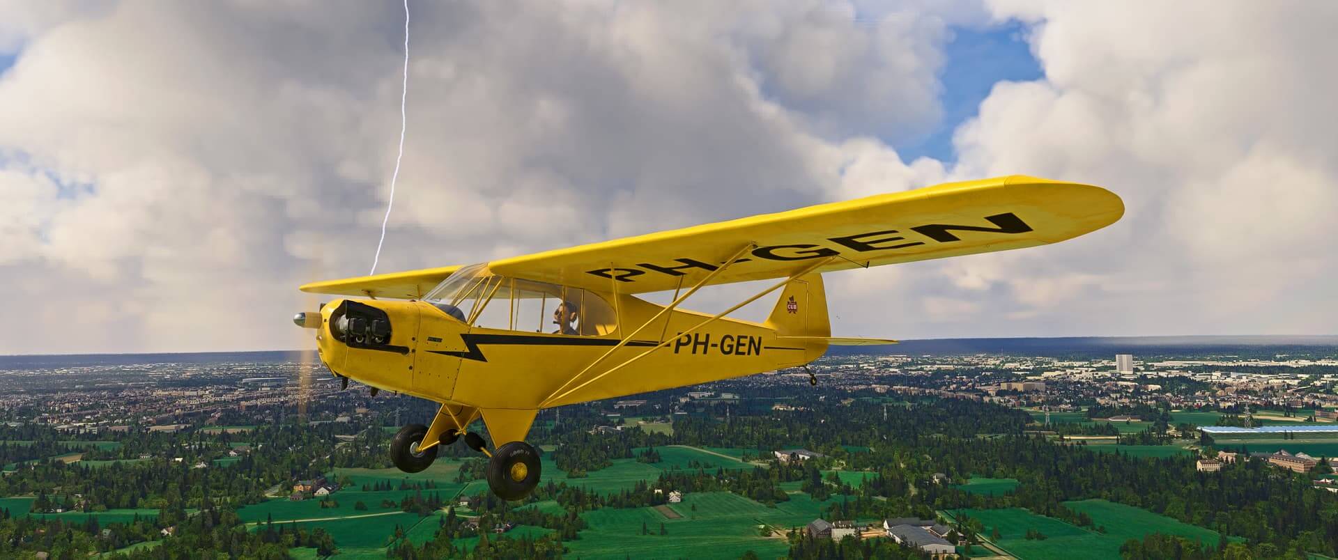 A yellow high wing general aviation aircraft cruises low over green fields, with a lightening bolt off of its right wing