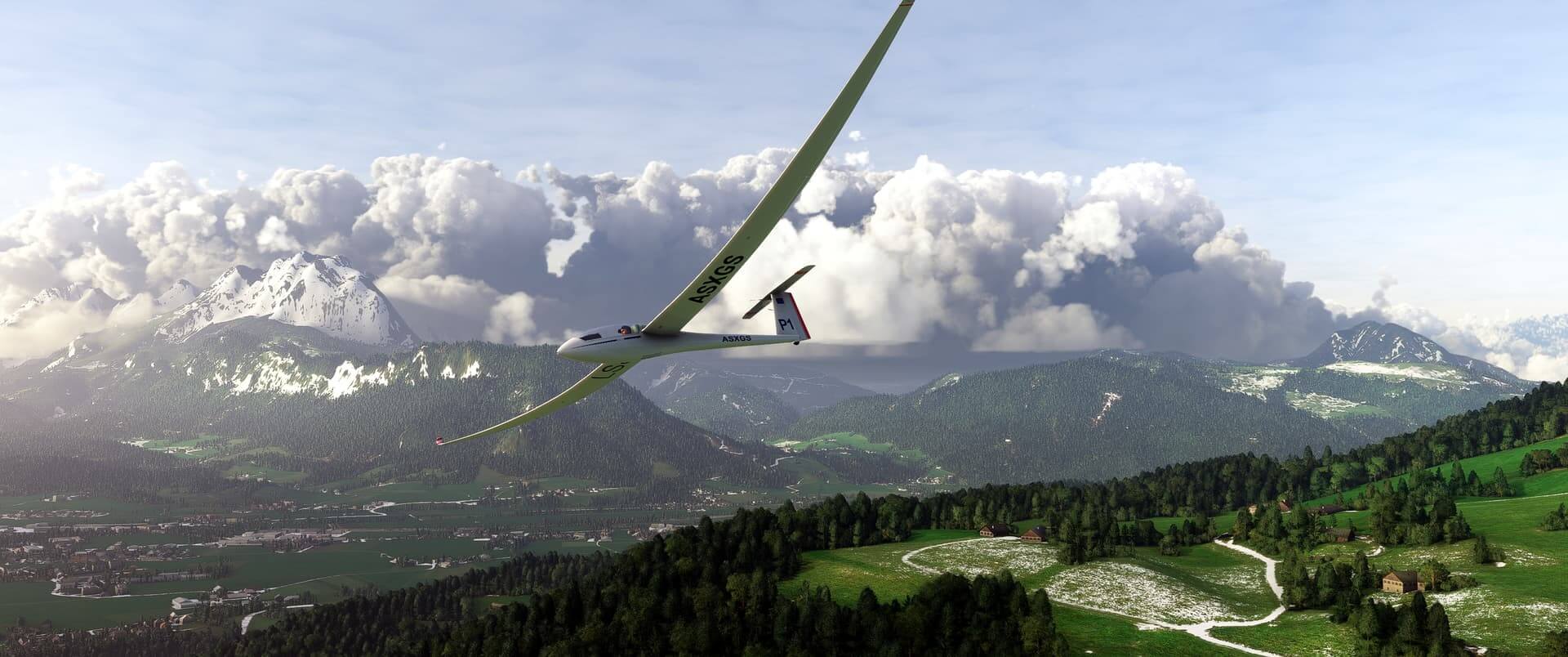 A glider banks left whilst flying in a mountain range valley