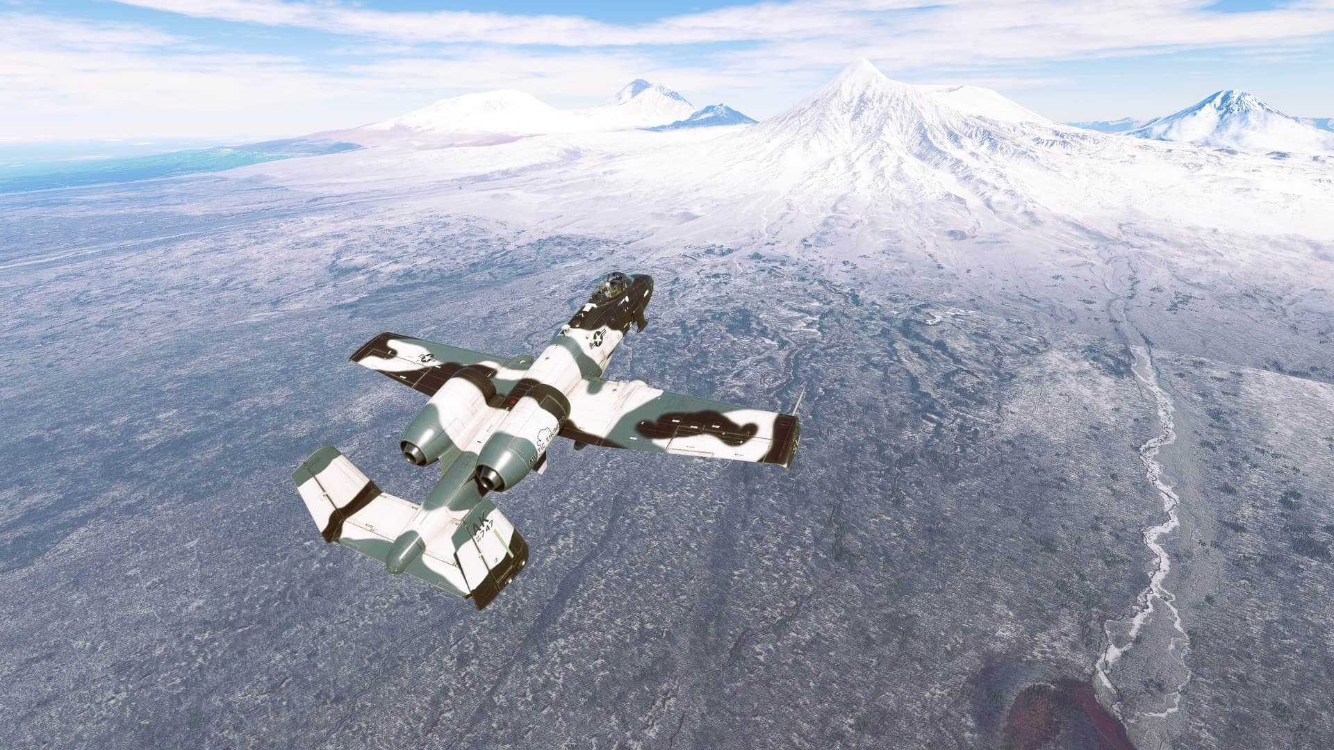 An A-10 Thunderbolt flies toward a snowy mountain range