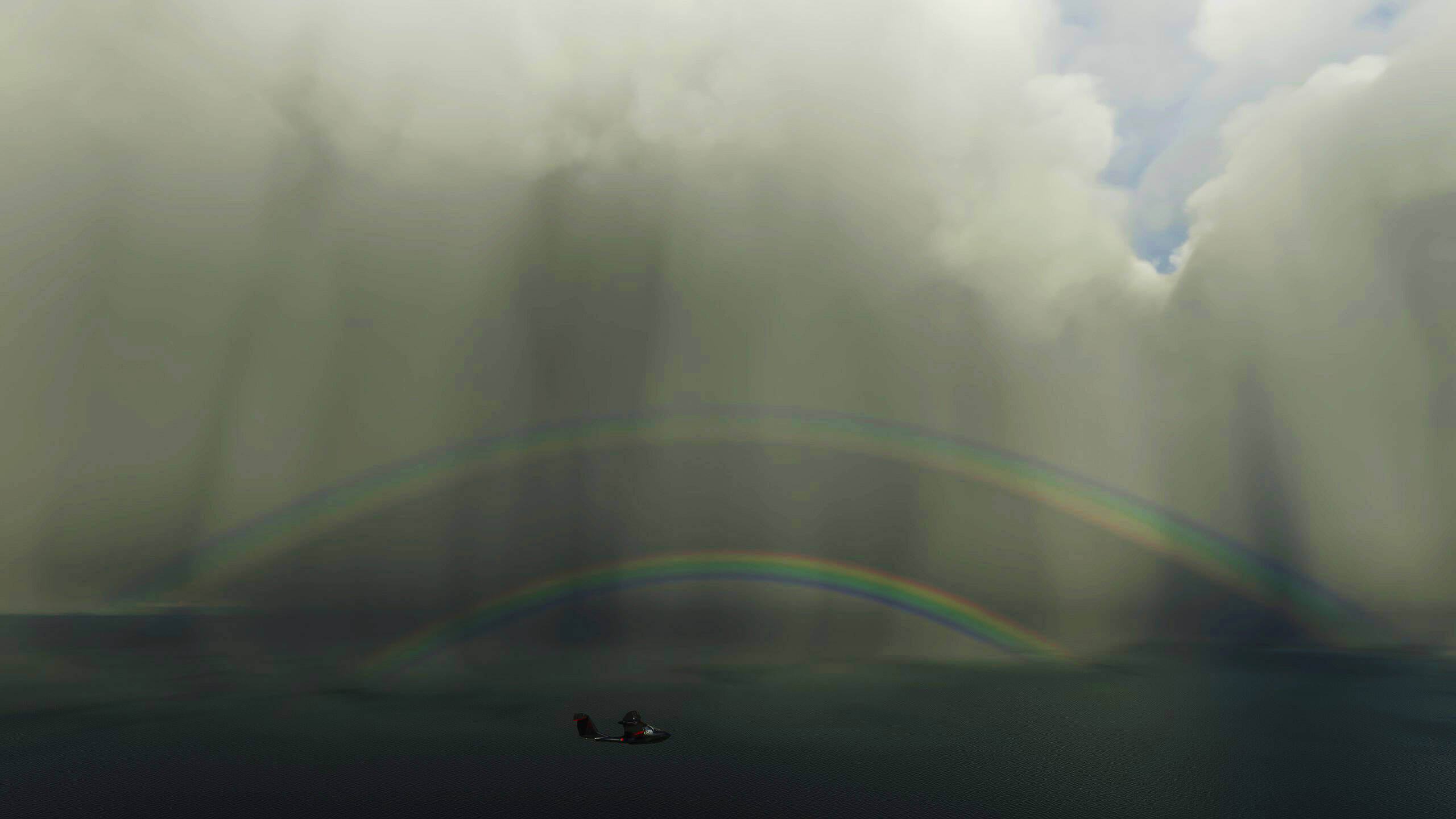 An Icon A5 flies near a double rainbow in amongst built up clouds and rain