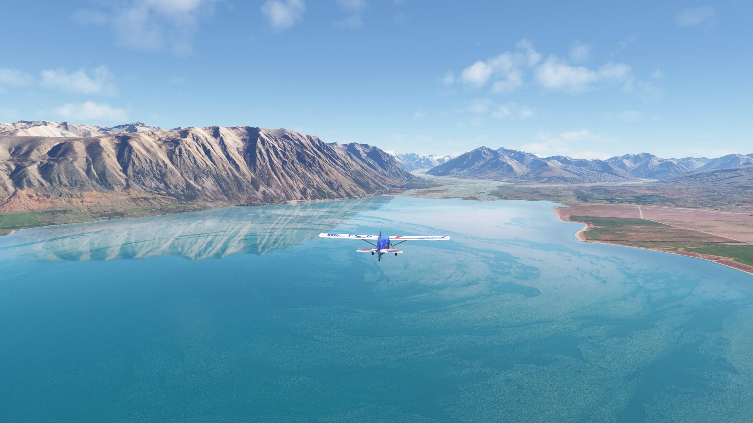 A Pilatus PC-6 Porter flies over a blue lake.