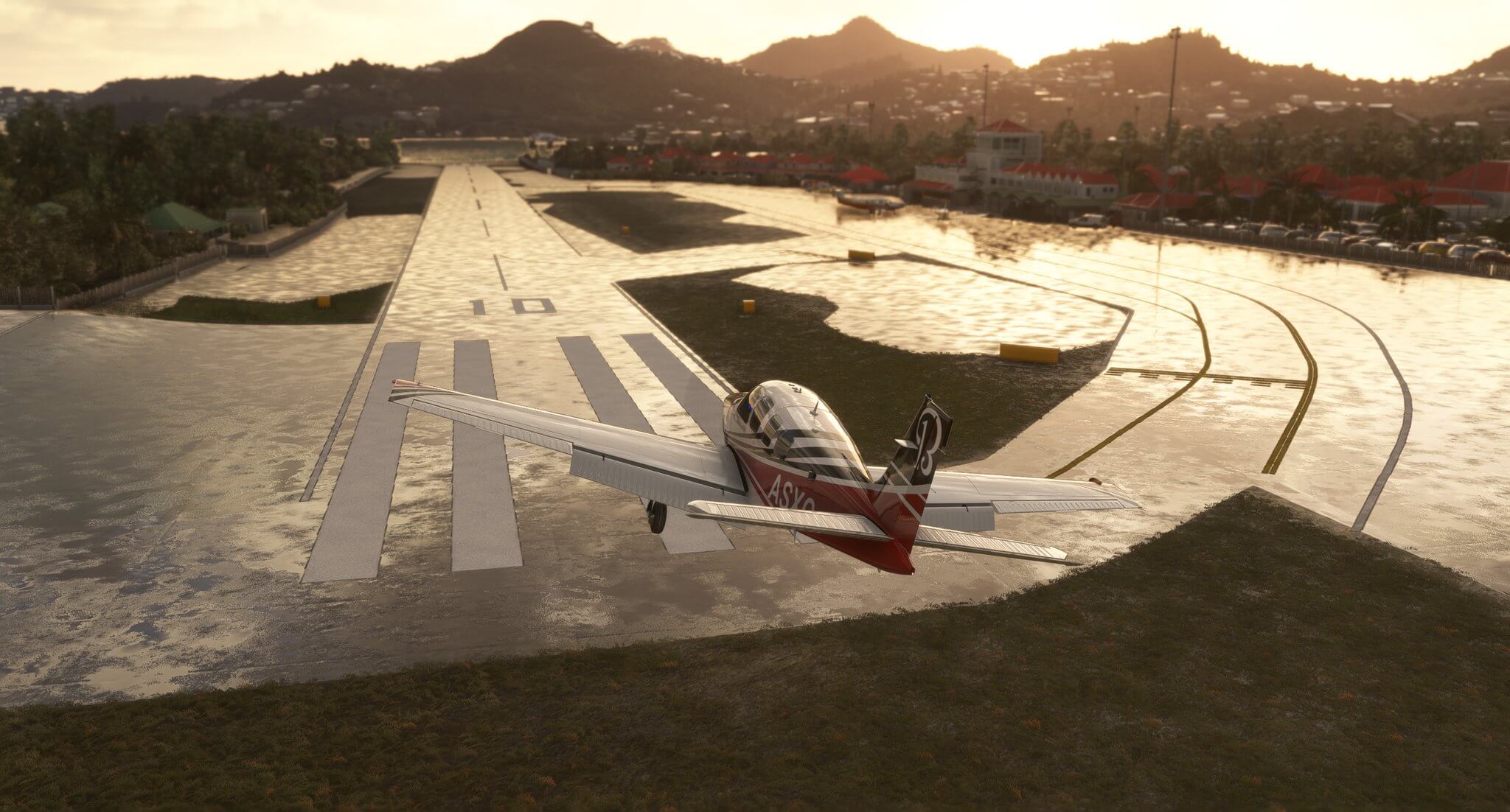 A Beechcraft low wing aircraft banks to the right before landing on a wet Caribbean runway