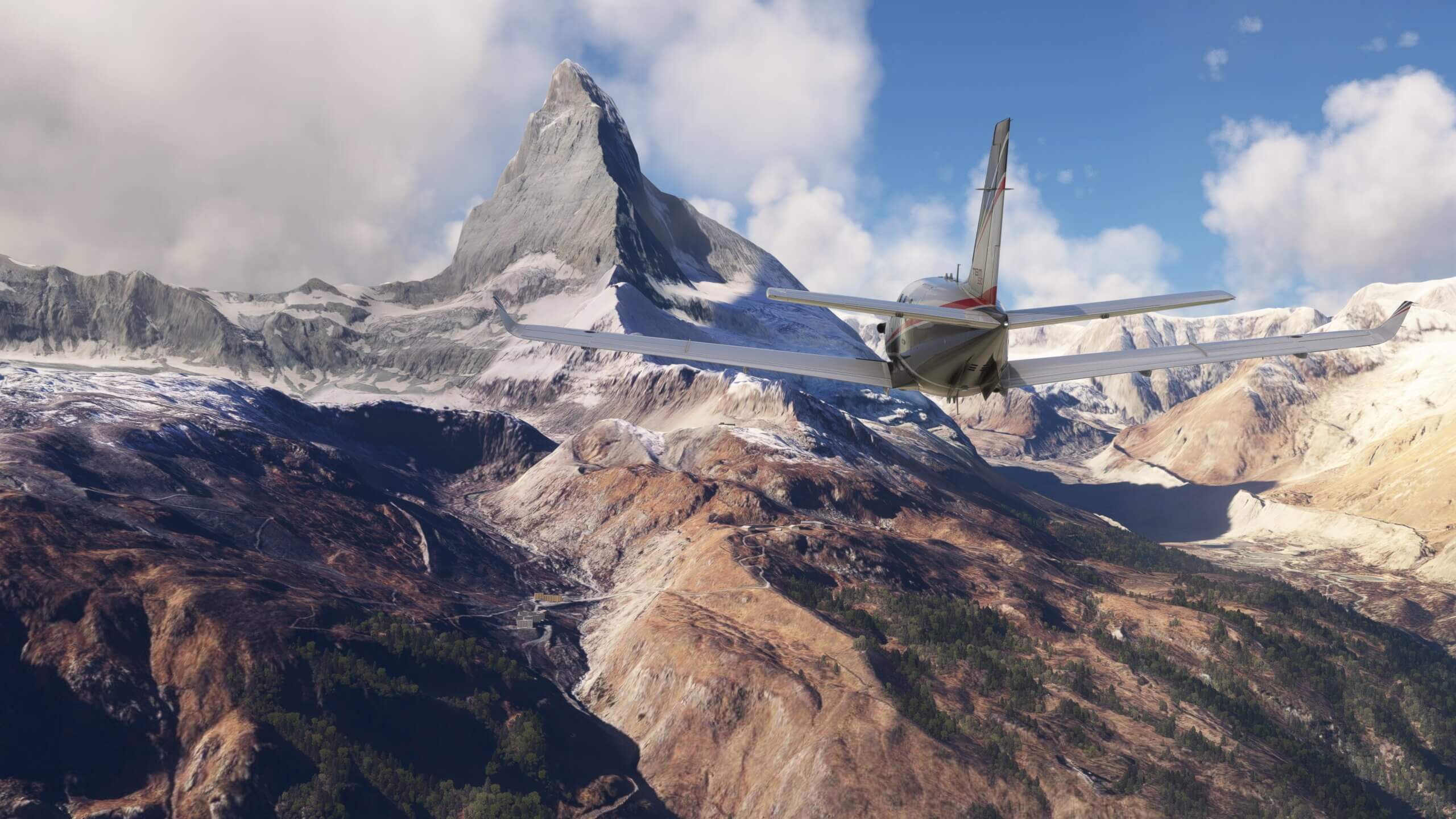 A TBM 930 flies towards a rocky mountain range