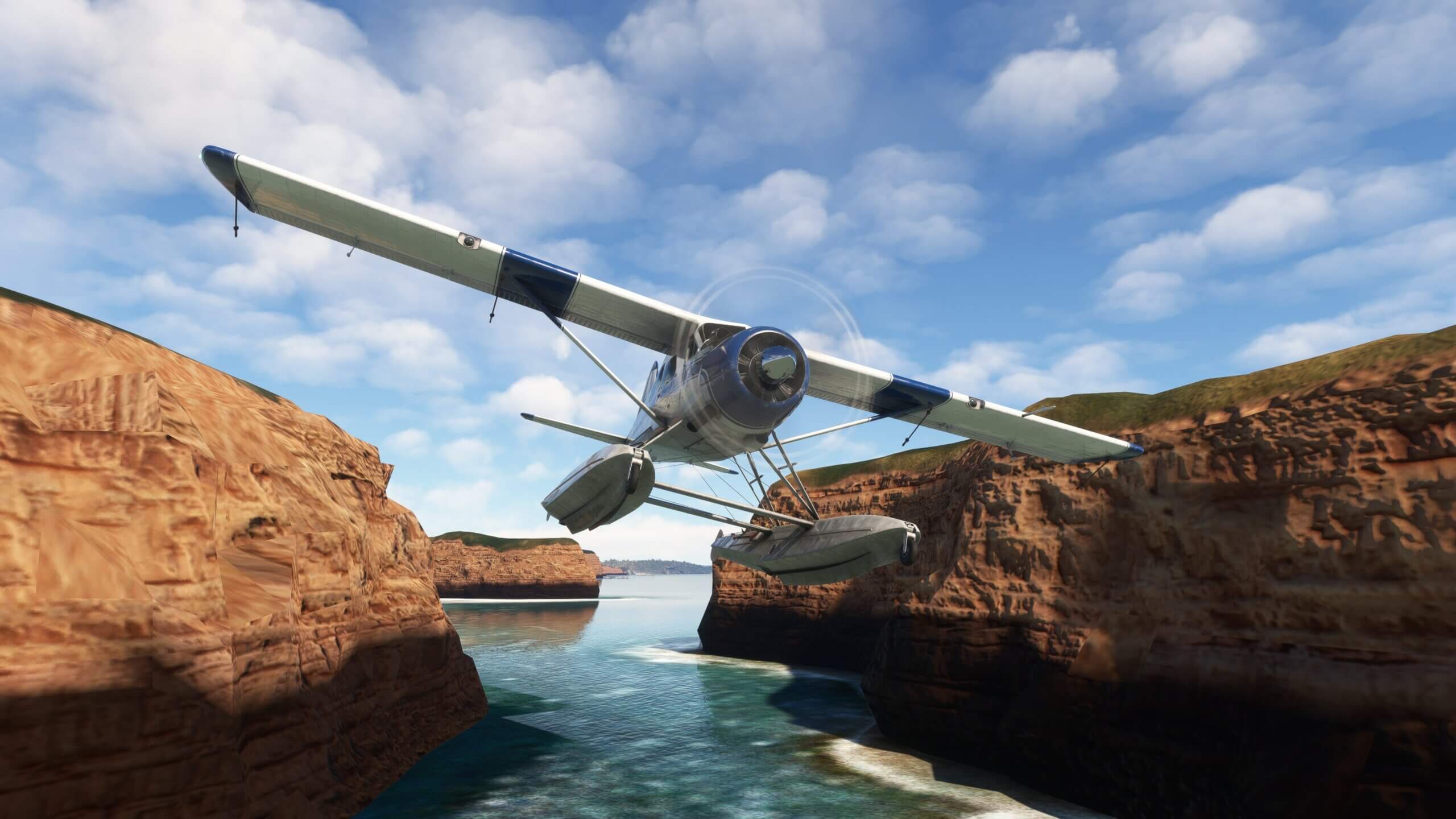 A propeller float aircraft passes through a rocky ravine