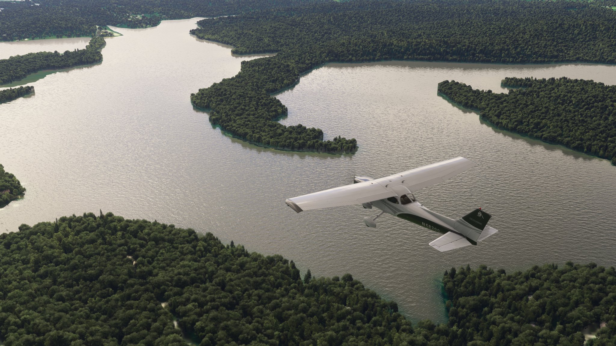 A Cessna 172 passes over a dense forest with a river flowing through