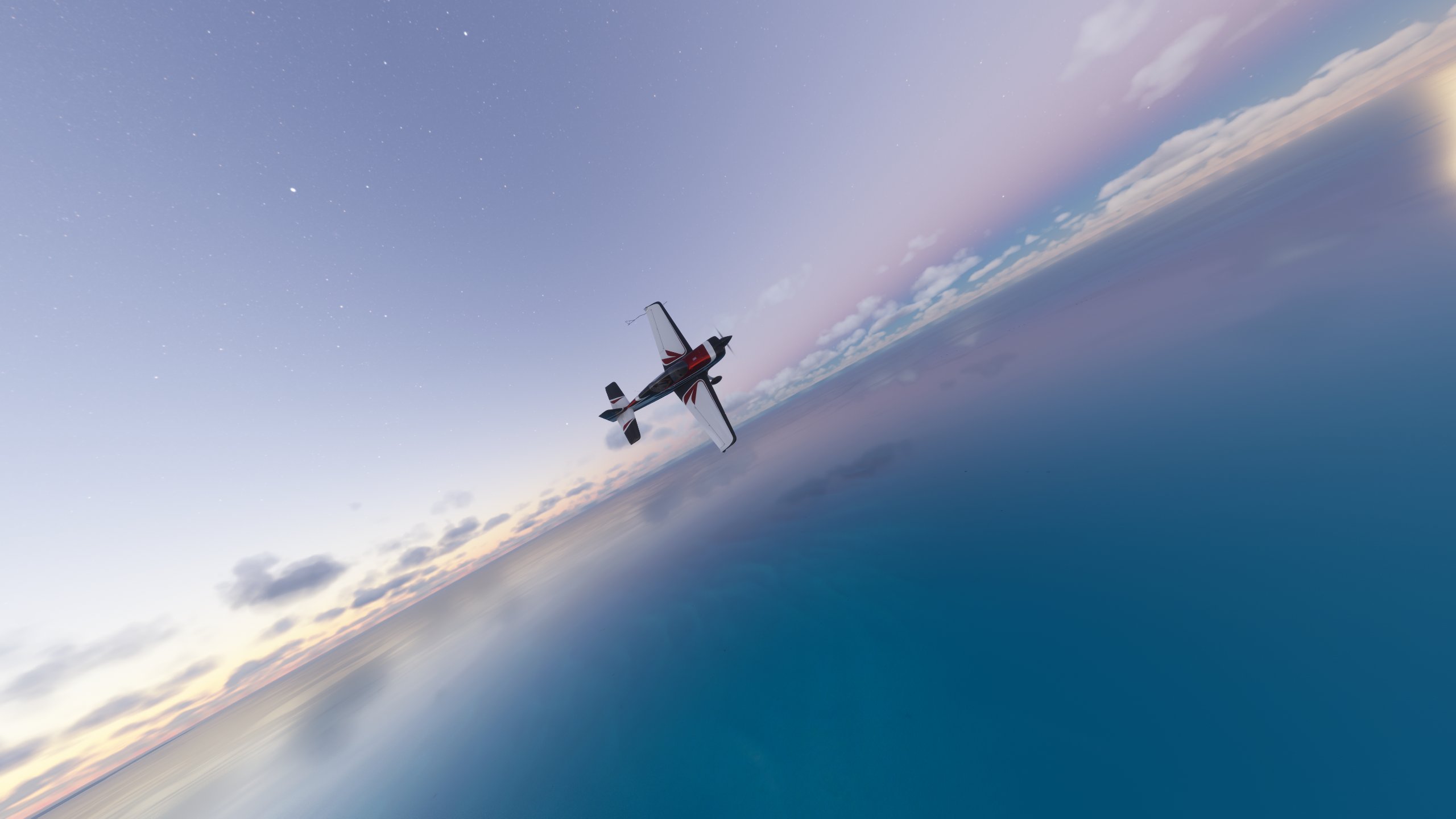 An aerobatic aircraft banks right whilst level with the horizon over water