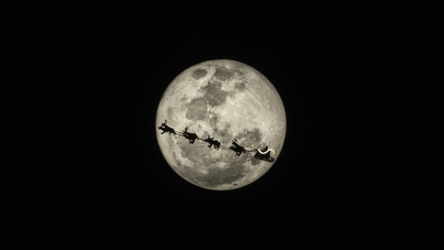 The silhouette of Santa and his sleigh in front of the moon