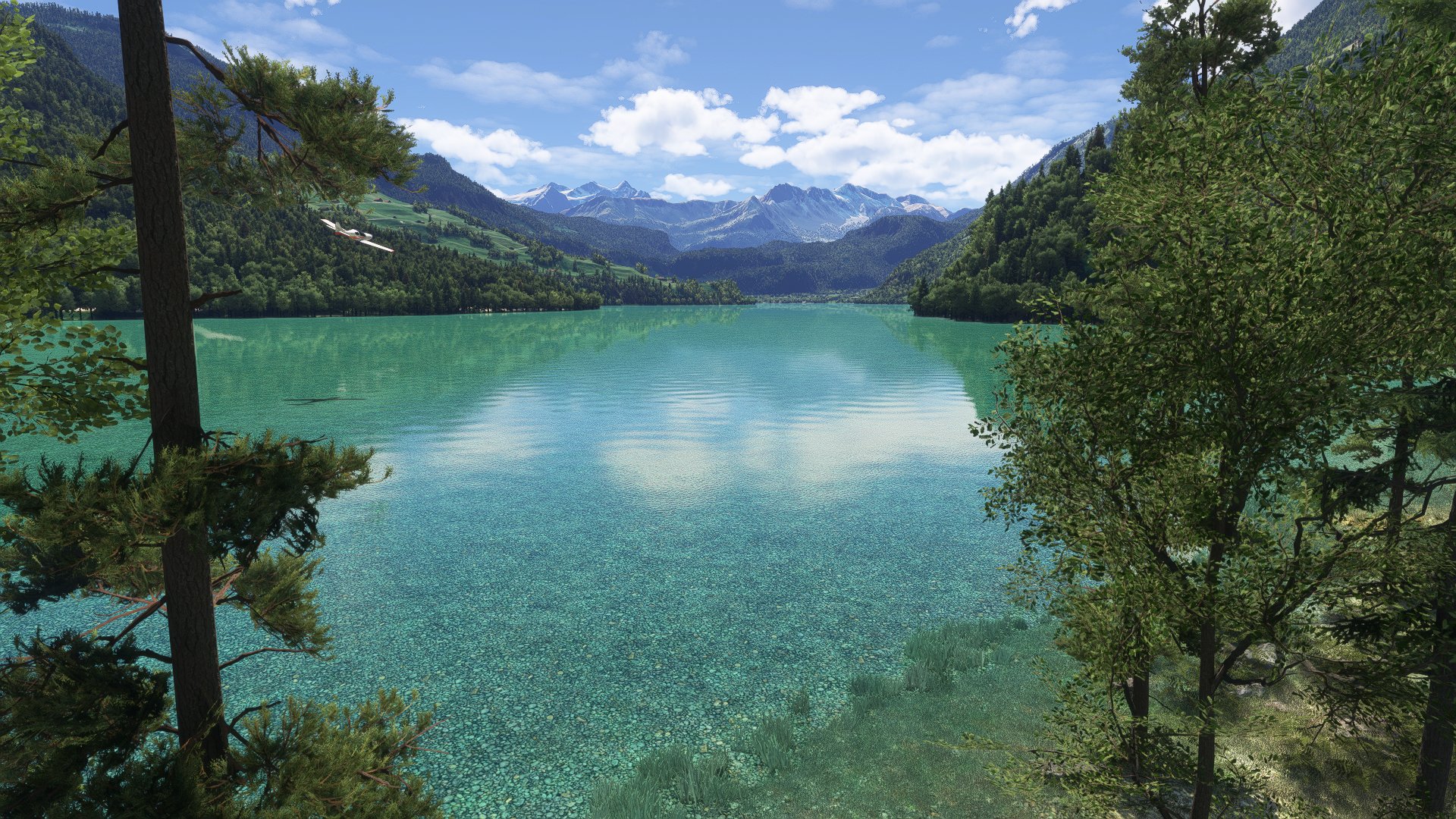 A propeller aircraft flies above water in a mountain valley