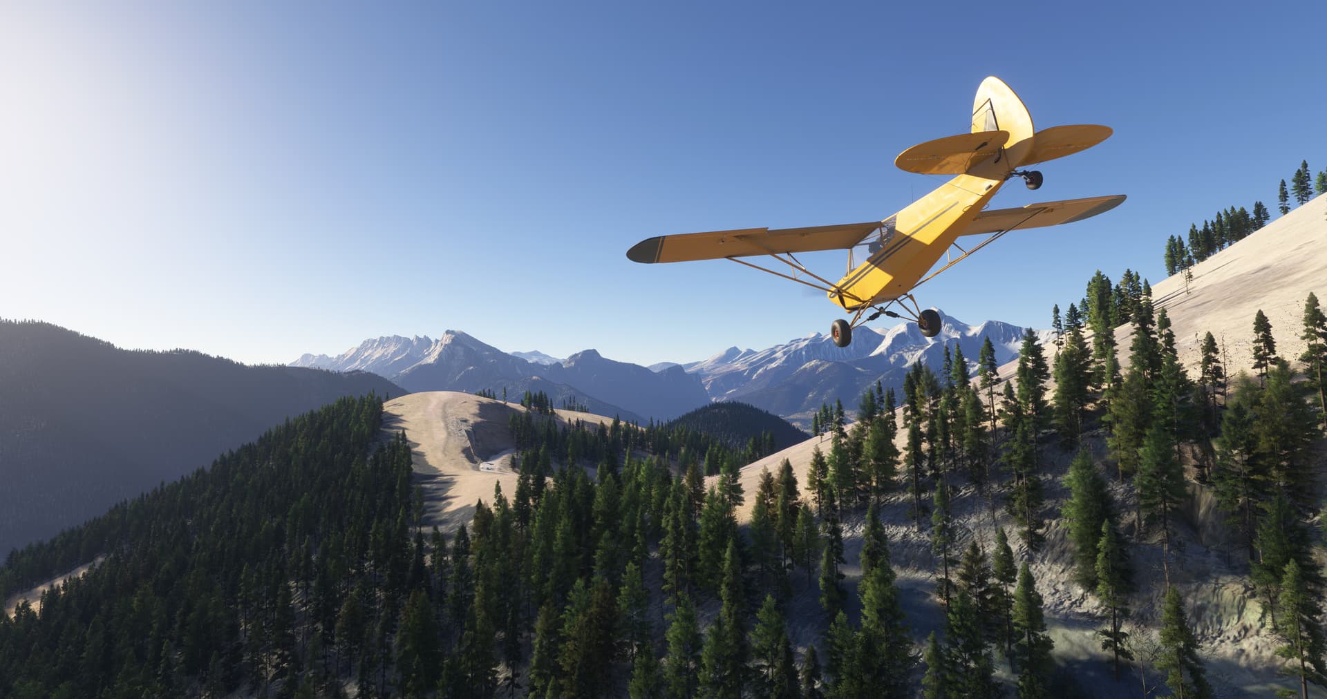 A high wing yellow propeller aircraft flies over a snowy mountain range