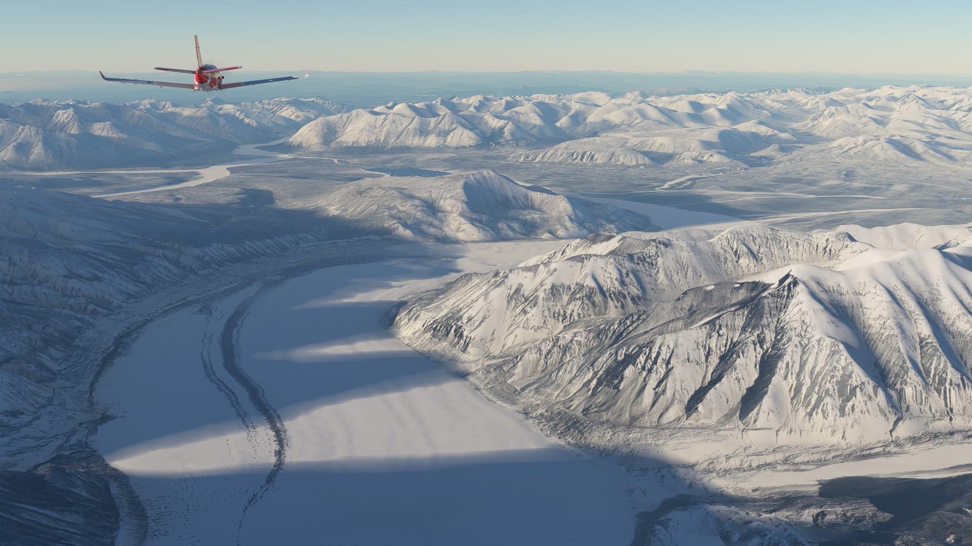 A red low wing propeller aircraft flies over a snowy mountain range