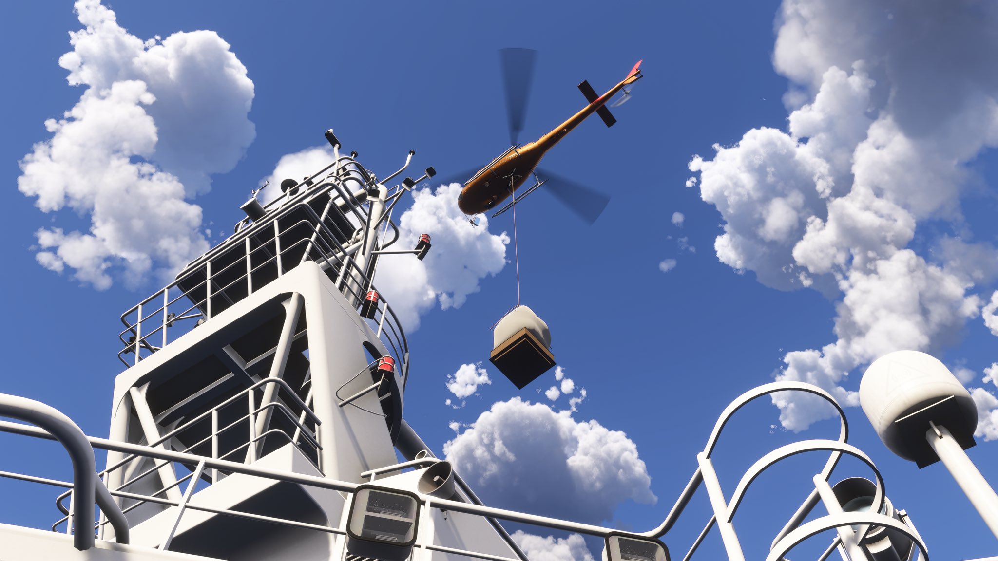 A helicopter moves into position to winch cargo onto a boat below