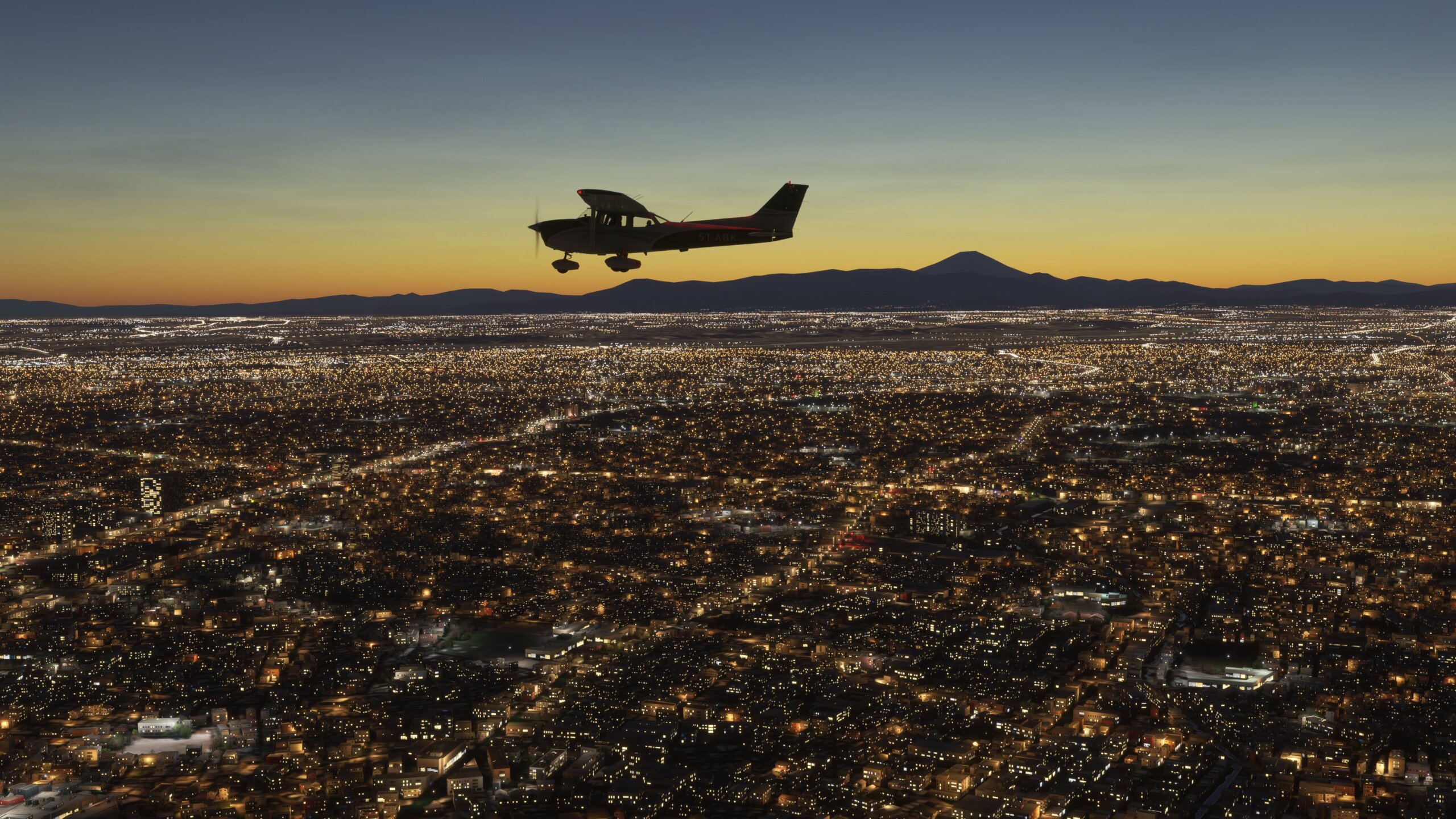 A Cessna 172 cruises above a large city, lit up at night time