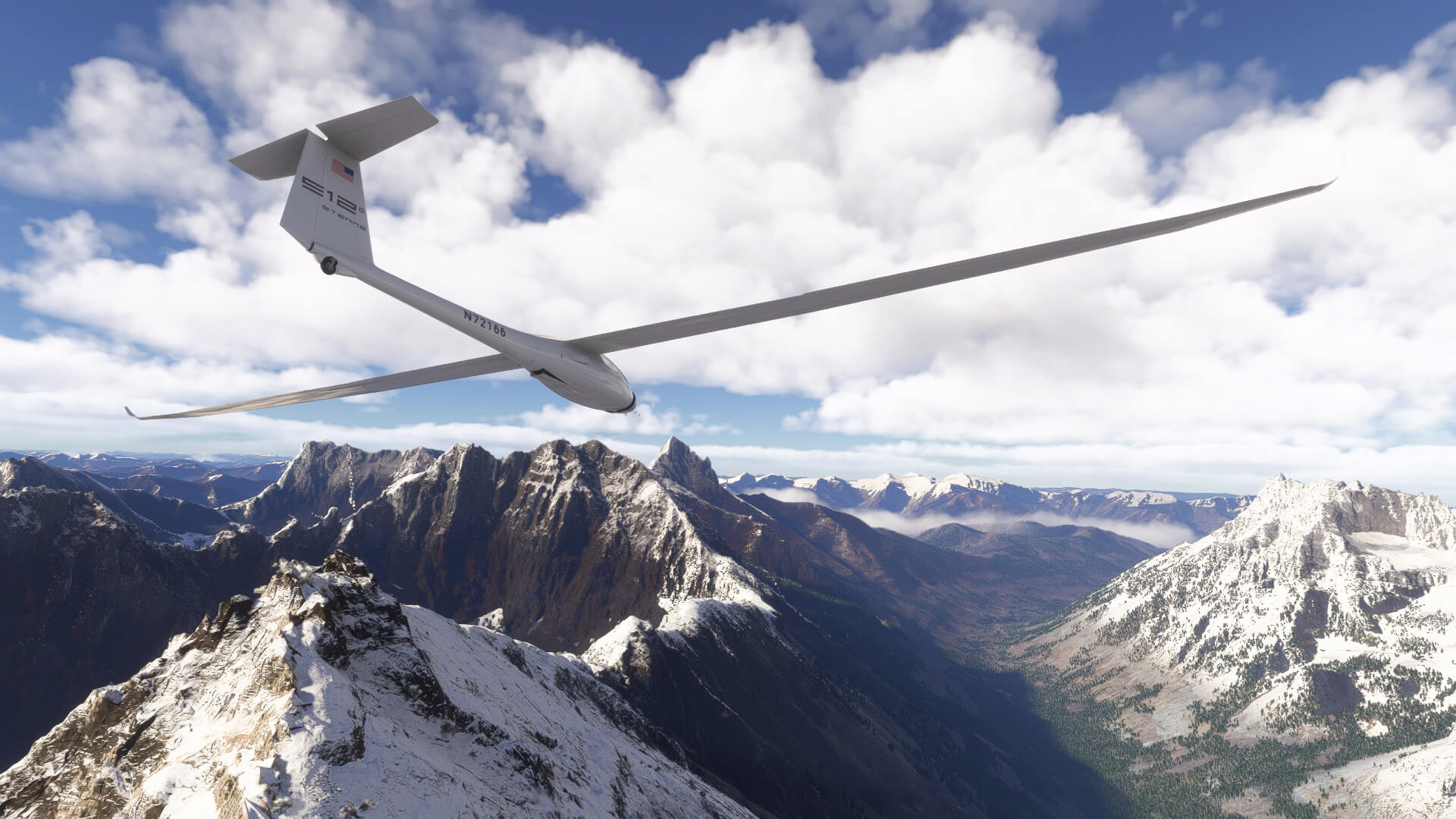 A glider dives towards a valley in amongst a mountain range