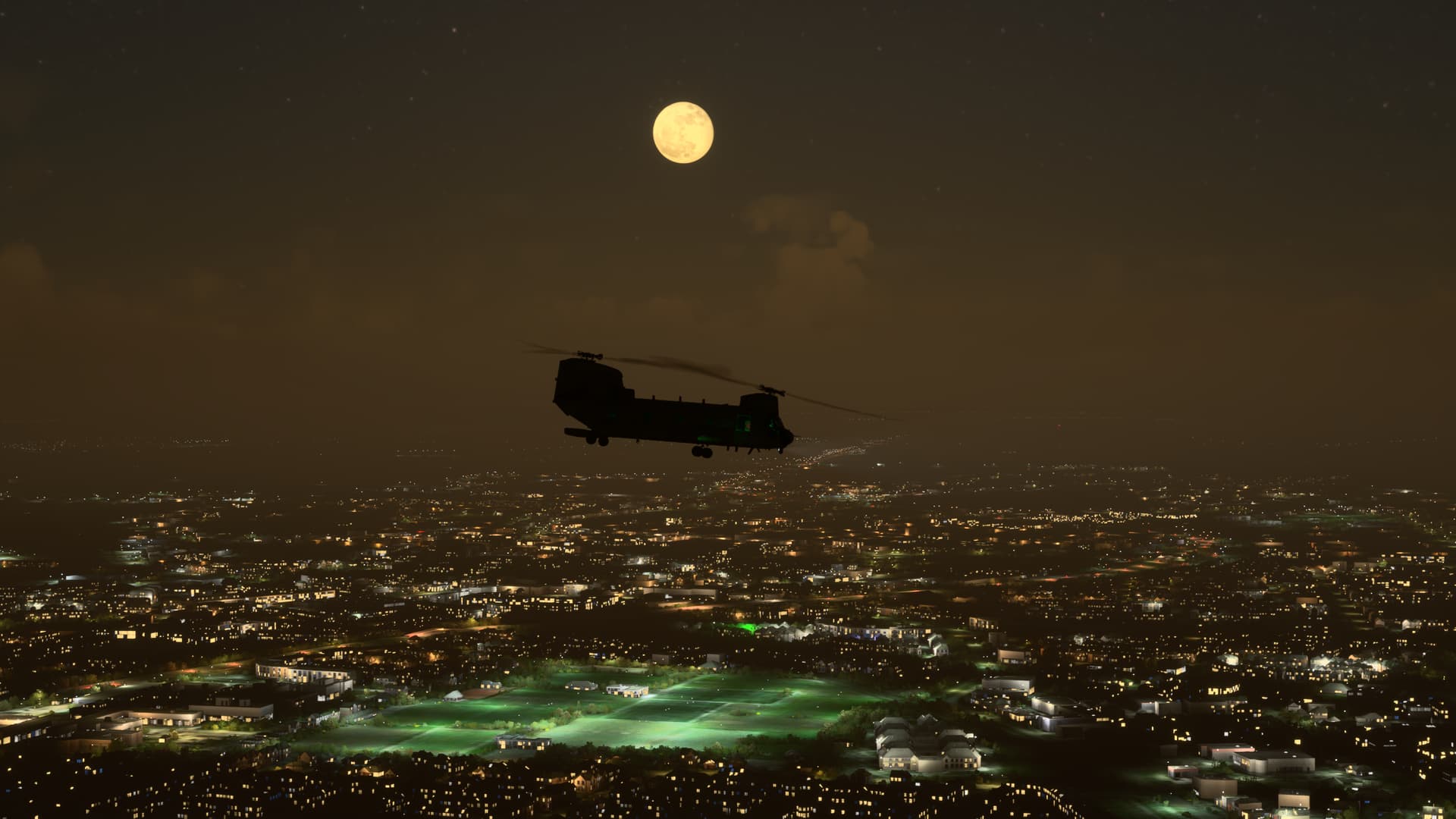 A Chinook cruises over a city at night with the moon above