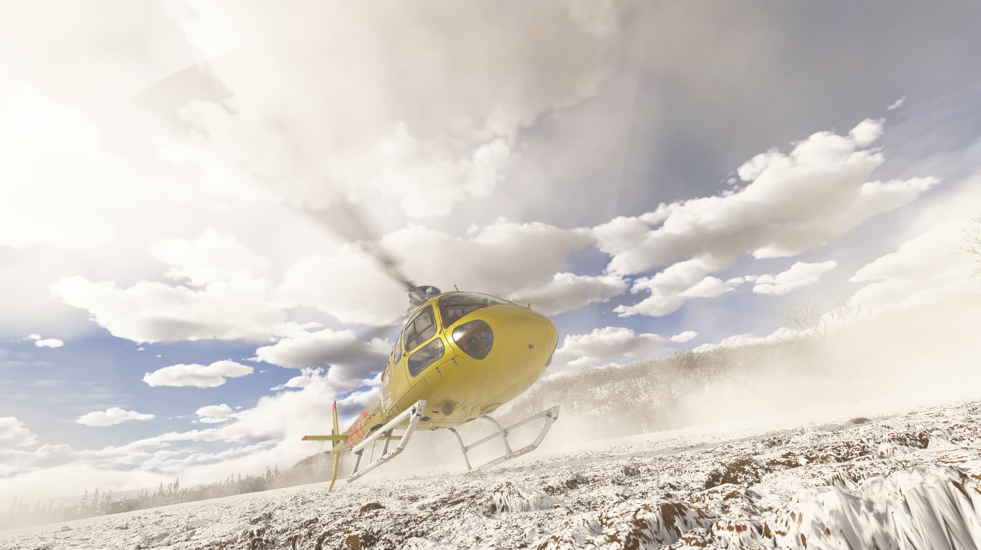 A yellow H125 helicopter touches its left skid down on a snow covered field