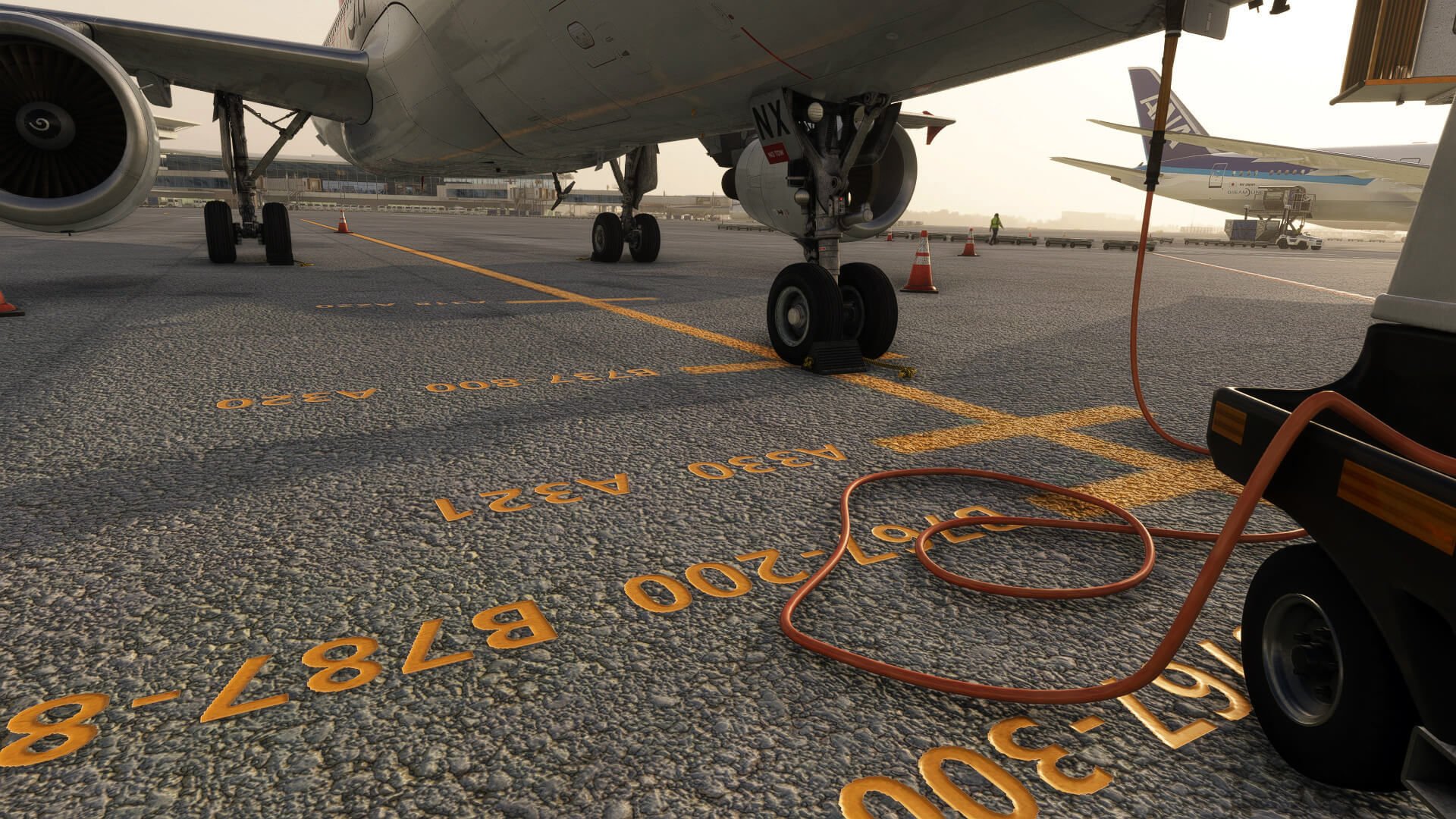 An airliner parked on stand with chocks and ground power unit attached