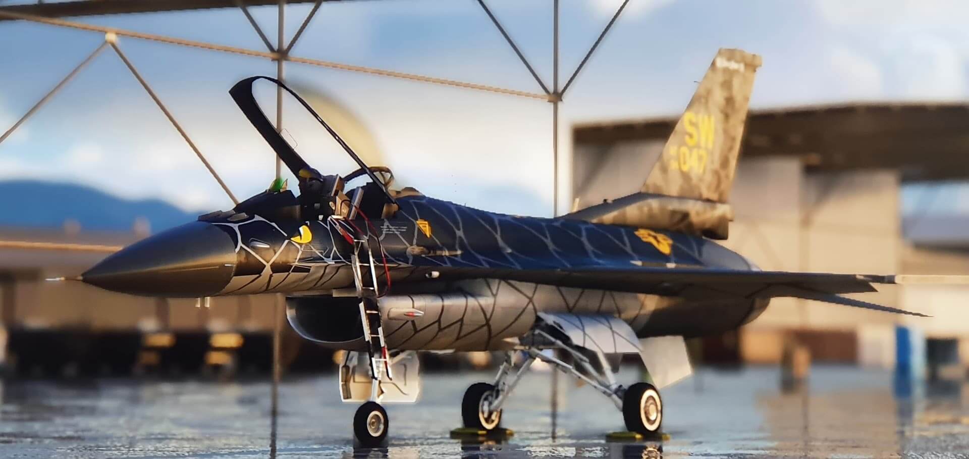 An F-16 in black snake like paint sits idle on the ramp with the cockpit canopy open