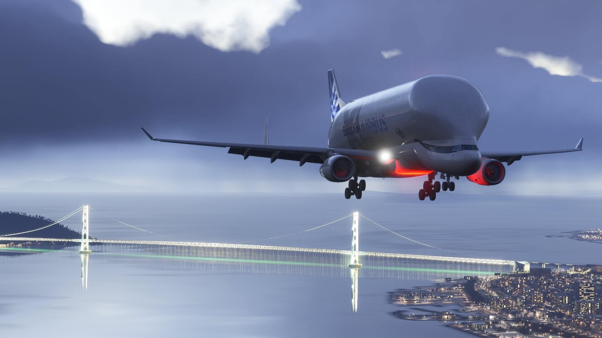 An Airbus Beluga XL with landing gear down on approach with a city bridge lit up behind