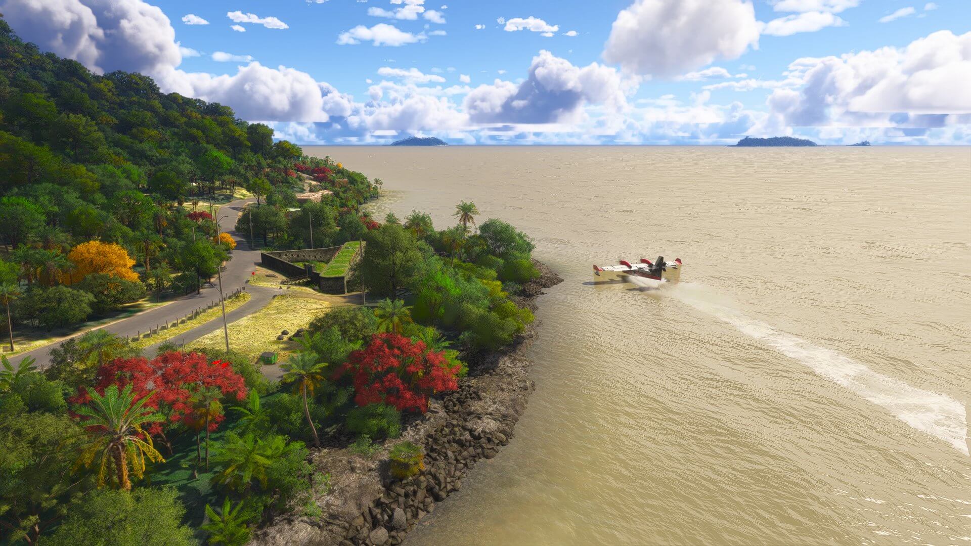 A white and red propeller aircraft lands on water next to a rocky shoreline