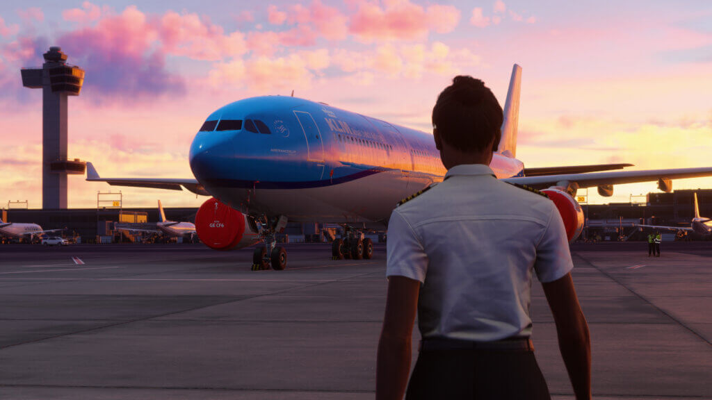 A pilot walks towards an airliner. The sun is just rising, making the sky pink.
