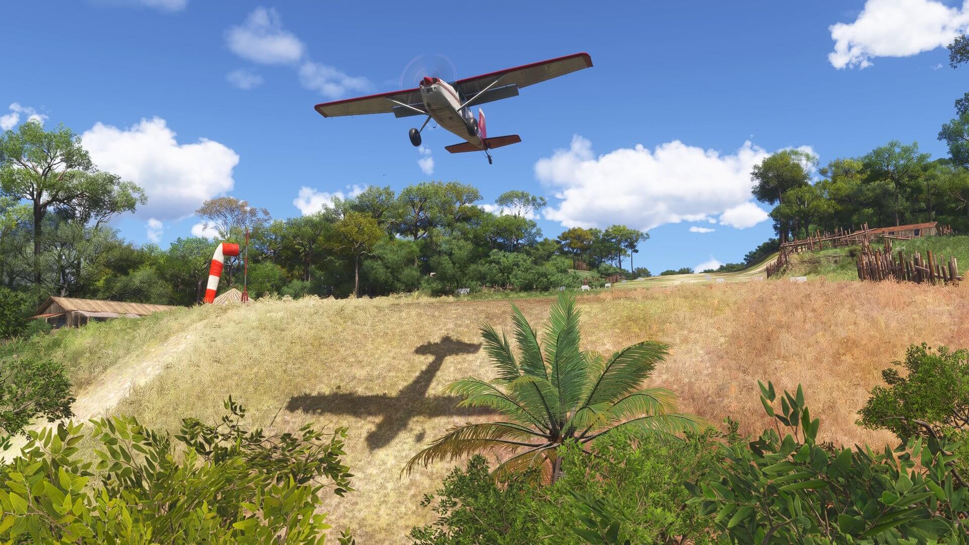 A Cessna high wing propeller aircraft takes off from a grass strip hill runway