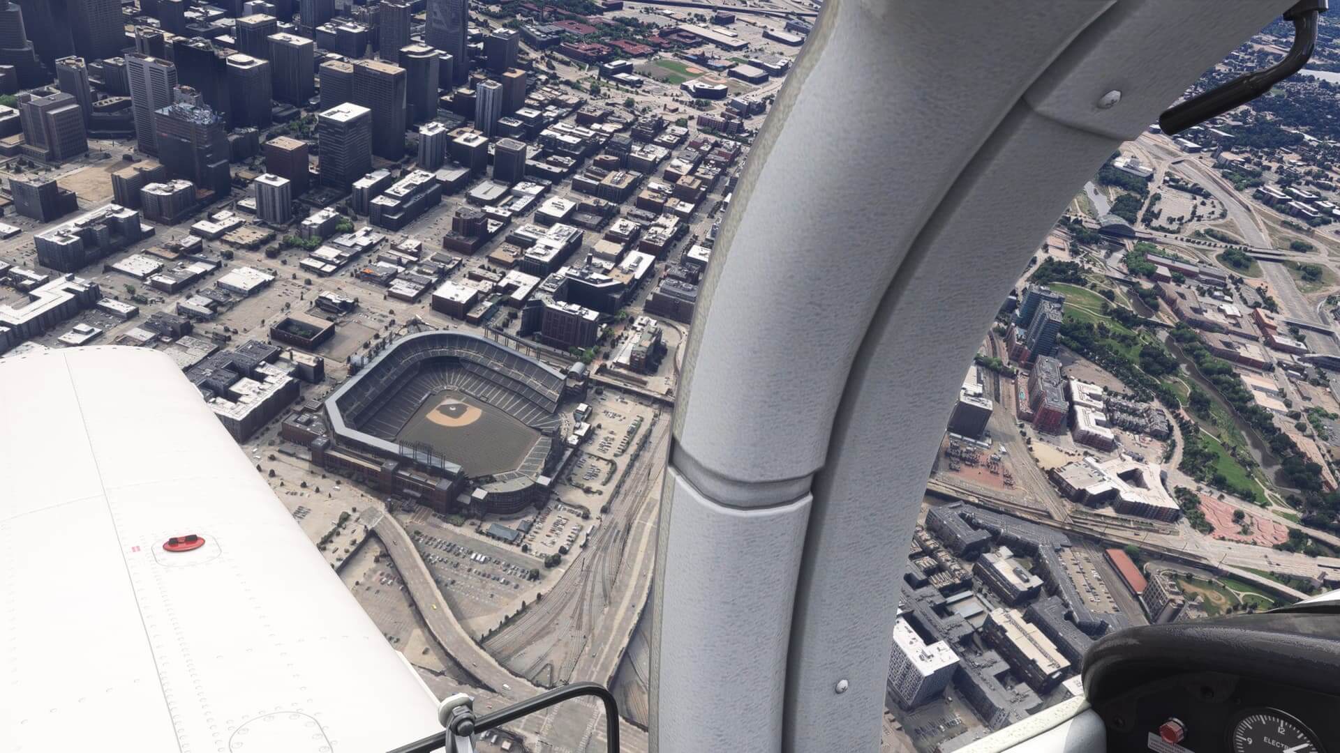 The view from the cockpit of a low wing general aviation aircraft as it banks left to get a view of a Baseball Field