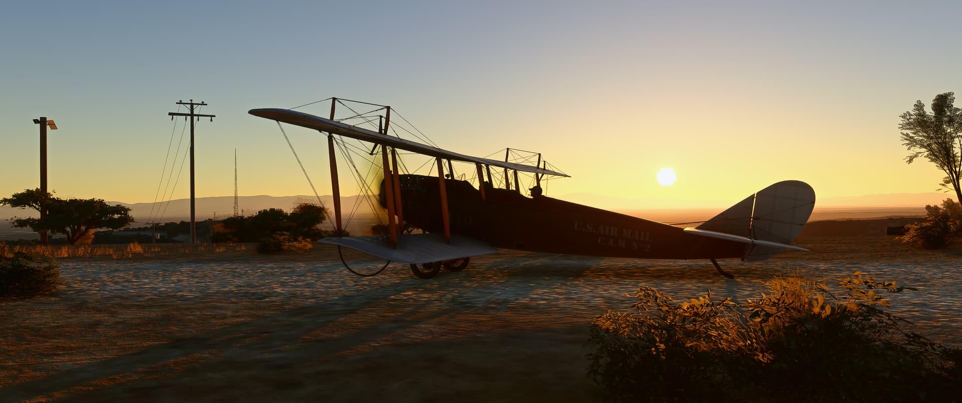 A dual wing propeller aircraft sits idle with the sun setting in the distance