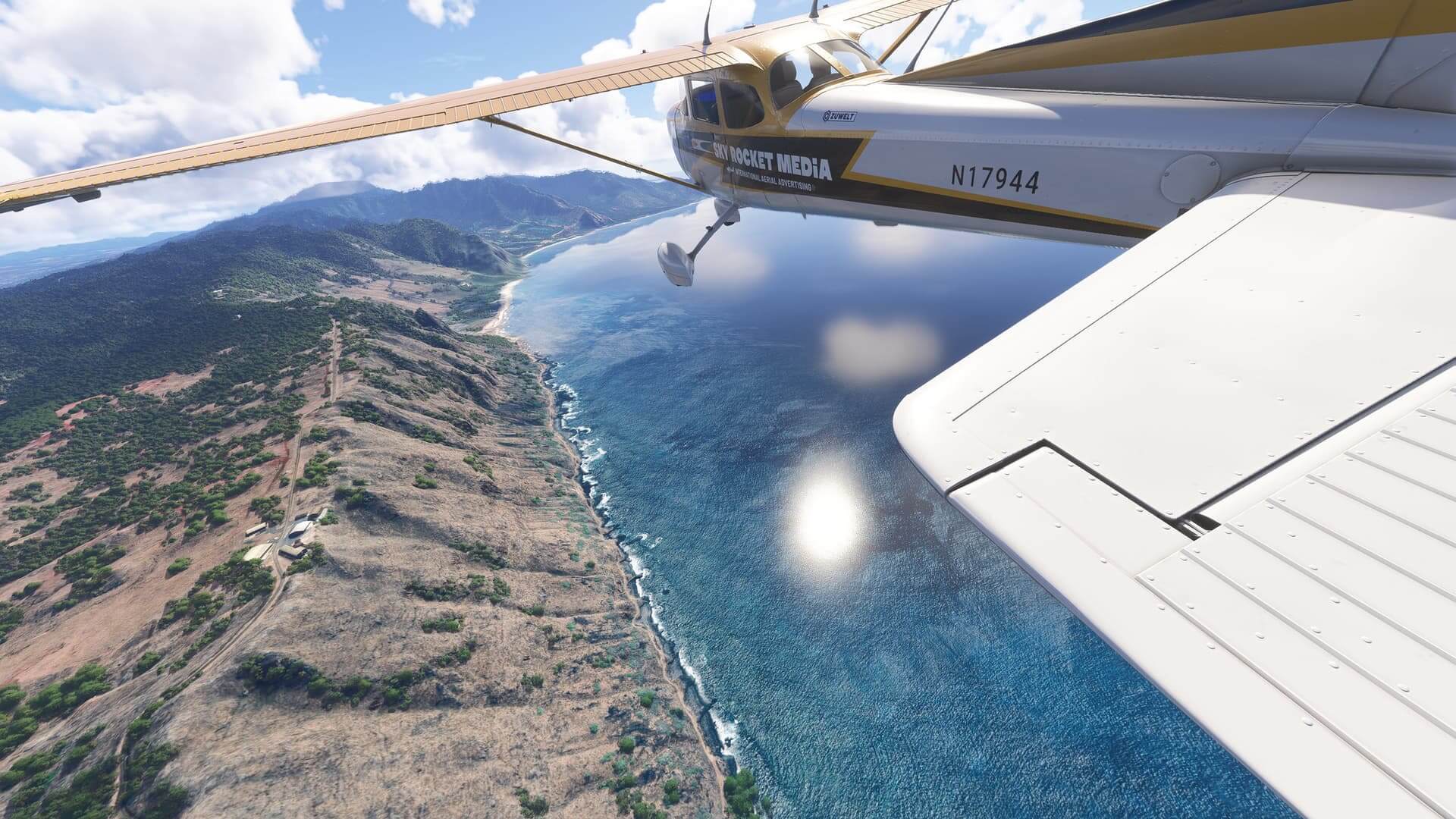 A Cessna 172 flies close to a rocky coastline