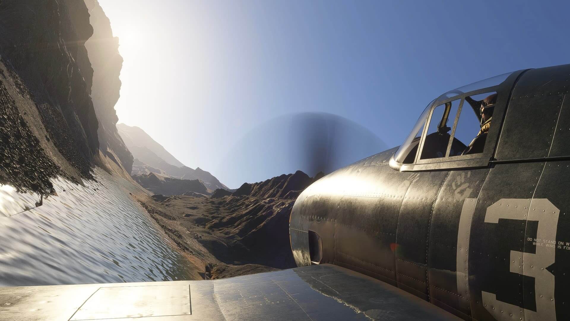 An airplane turns as it flies through a gorge above a river.