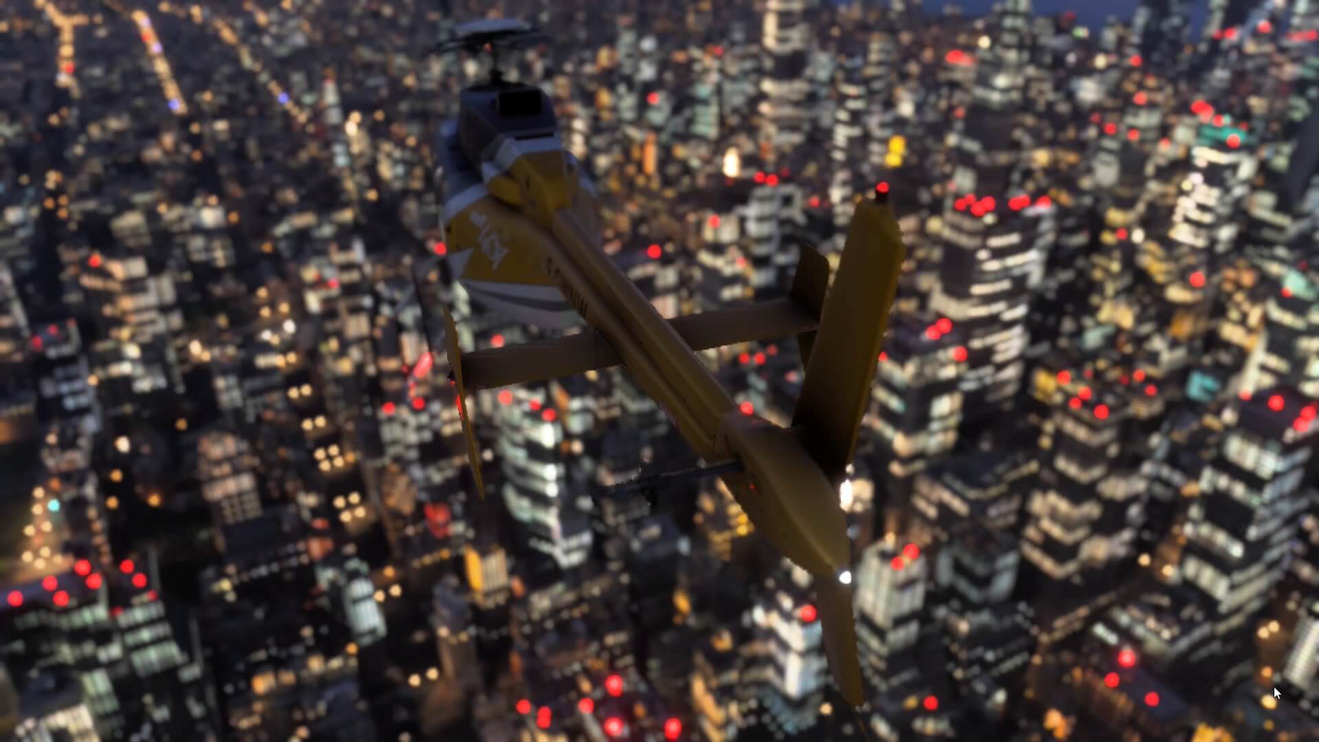 The view of a yellow Bell 407 helicopter overhead a cityscape at night