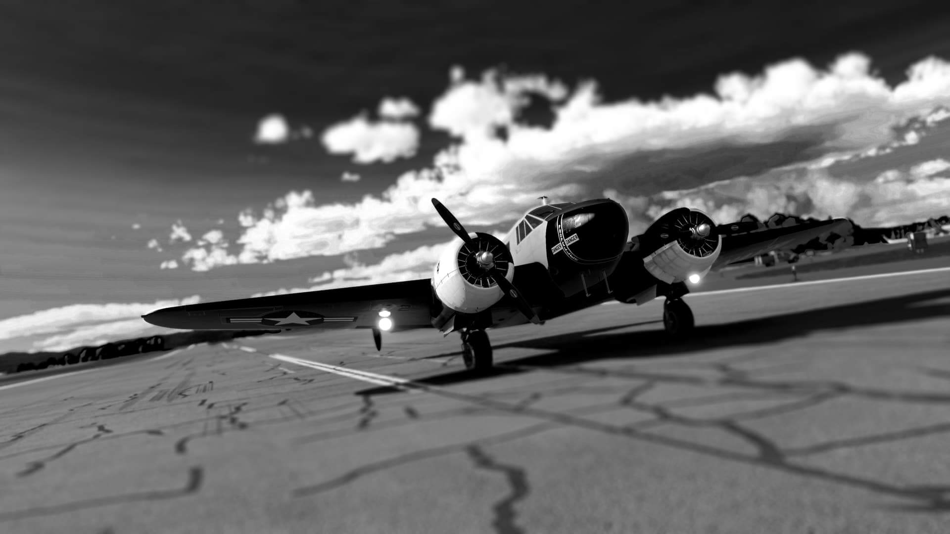 A dual wing propeller aircraft with landing lights on in black and white color
