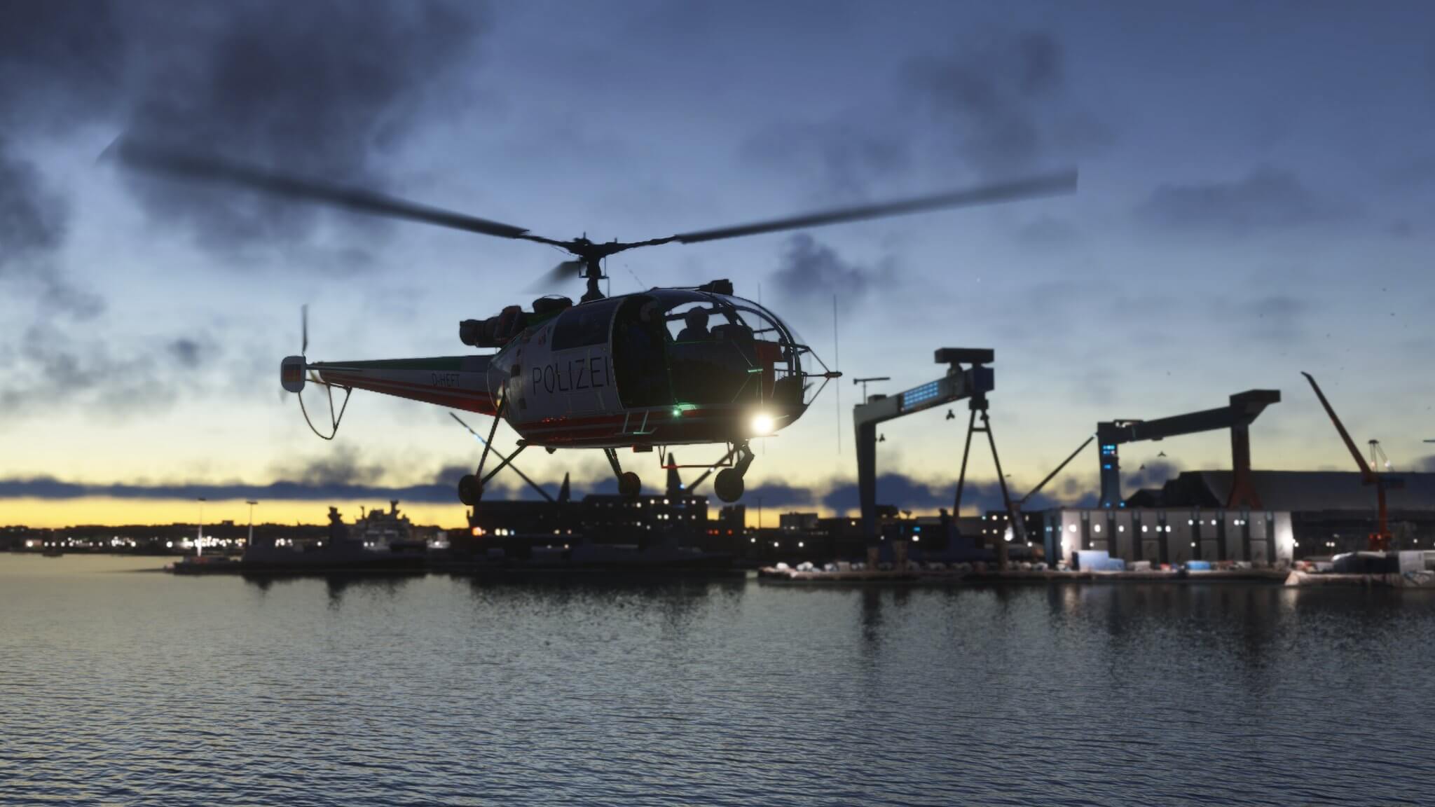 A Polizei helicopter hovers low over water near a dockyard