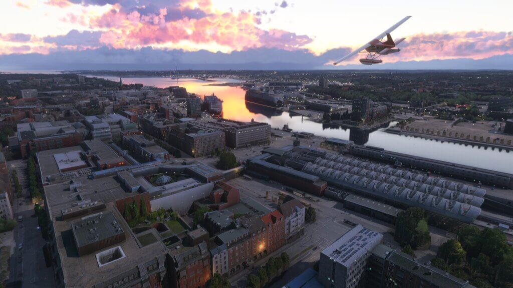 A Cessna 172 banks left over a city during sunset