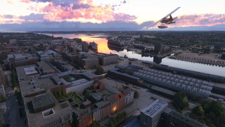 A Cessna 172 banks left over a city during sunset