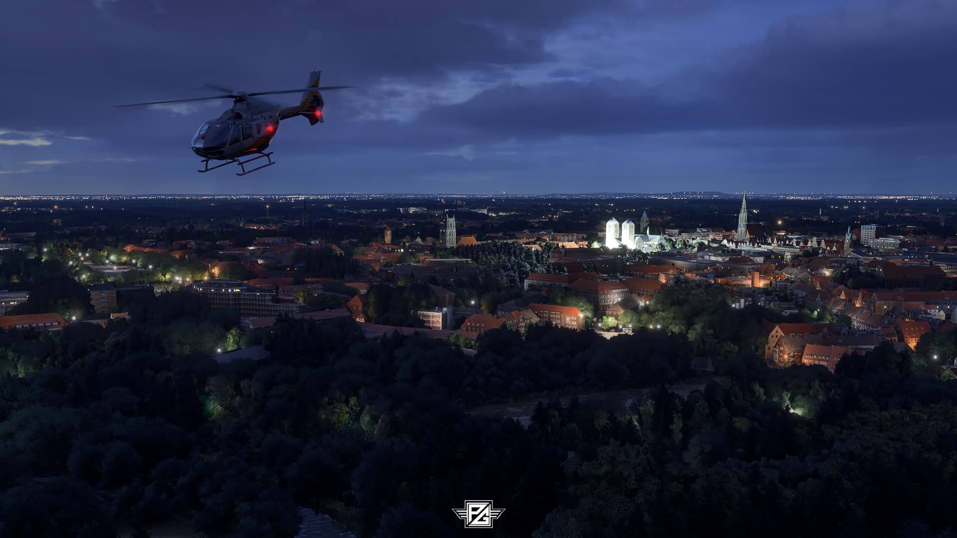 An EC135 helicopter makes a night time flight over a busy cityscape