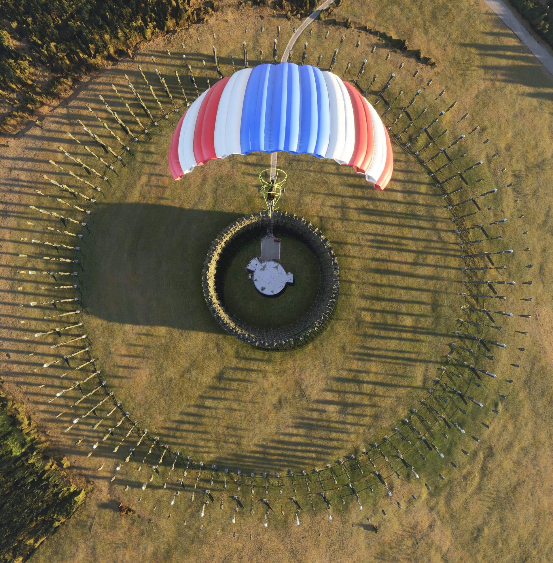 A para-glider aircraft flies over a circular monument