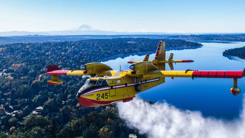 A CL-415 drops water on a forest fire.