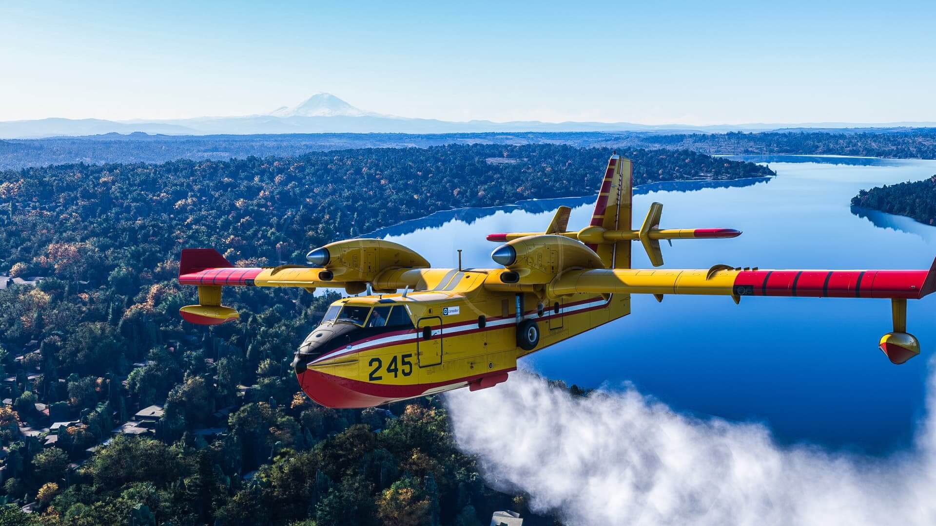 A CL-415 drops water on a forest fire.