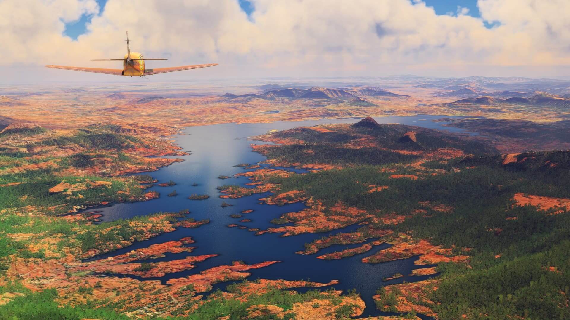 A yellow painted low-wing propeller aircraft cruises over an orange colored desert landscape