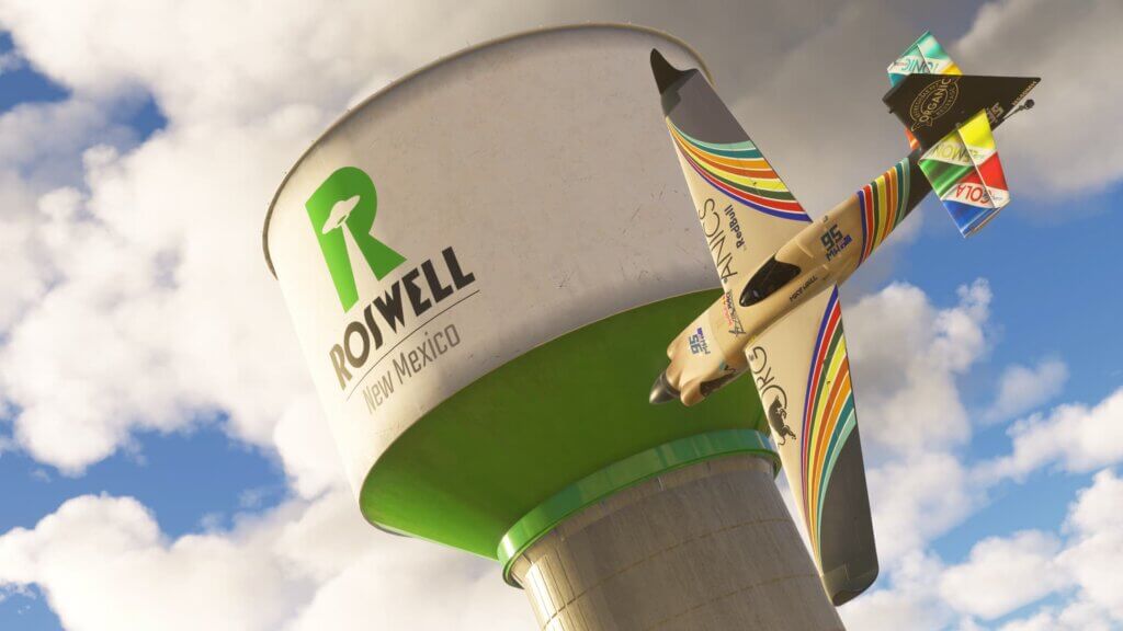 A Red Bull Racing aircraft banks sharply to the right whilst flying past a Roswell New Mexico sign
