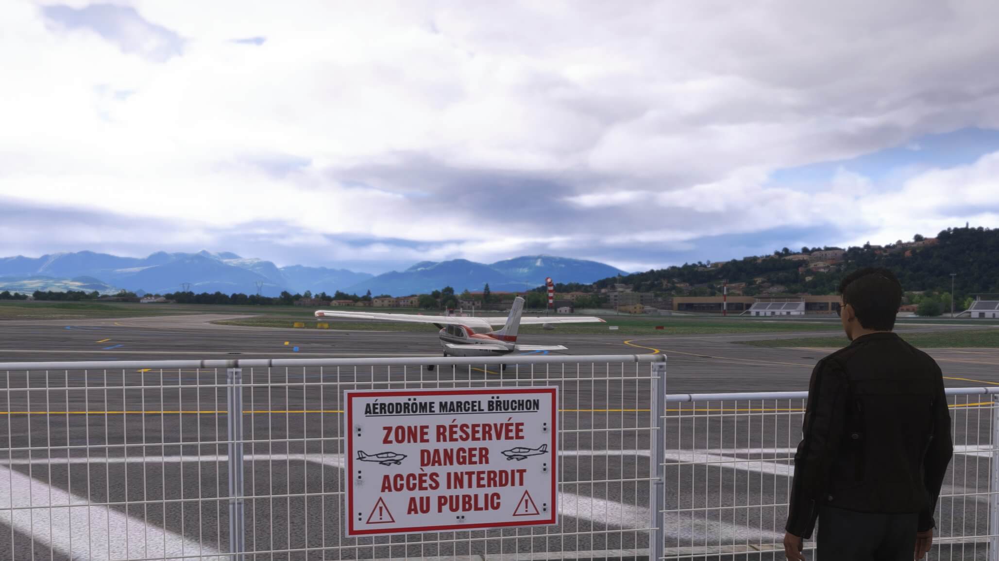 A pilot looks out over an apron towards a Cessna 172 aircraft parked on the ramp
