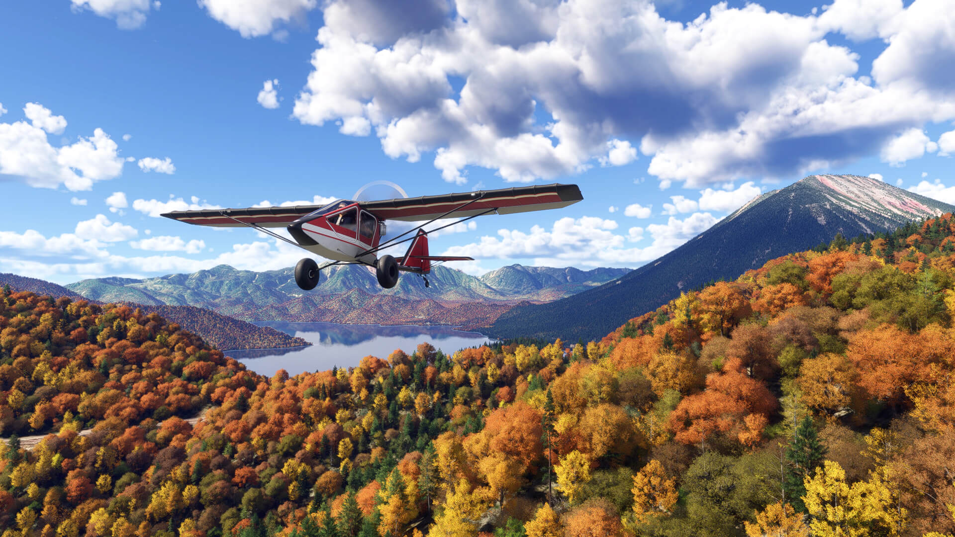 A high wing propeller aircraft flies low over trees whilst flying along a valley
