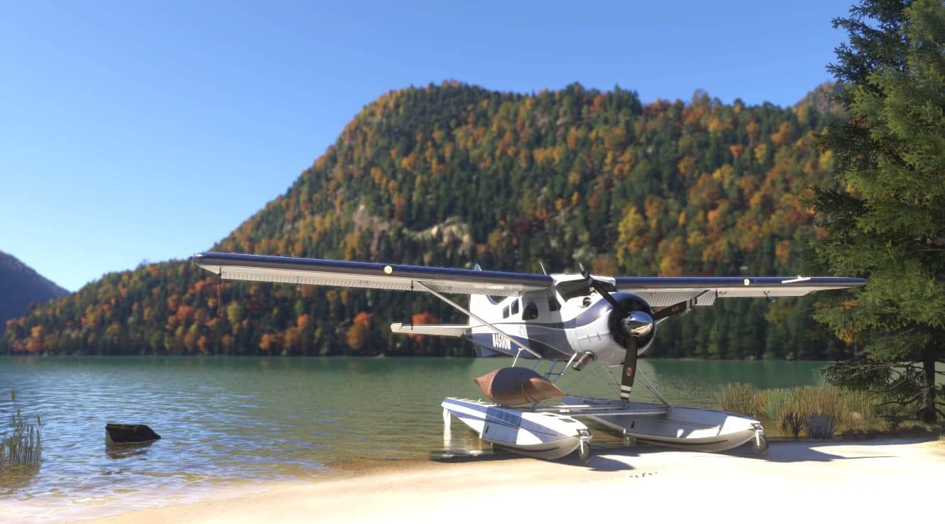A high-wing propeller aircraft on water ski's parked up on the edge of a lake
